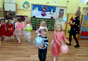Dzieci oraz nauczycielka tańczą z balonami, trzymając je w rękach.