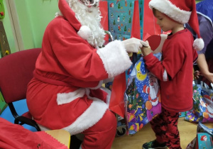 Mikołaj wręcza prezent chłopcu.