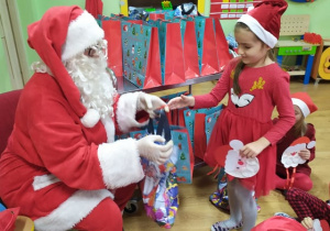 Mikołaj wręcza prezent dziewczynce.