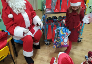Mikołaj wręcza prezent dziewczynce.