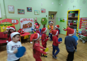 Dzieci trzymają obręcze - kierownice i poruszają się po sali przy piosence: Mikołaj jedzie samochodem.. "