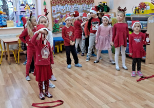 Przedszkolaki stoją przygotowane do zabawy ruchowej "Zanieś i przynieś koszyczek z Mikołajem".