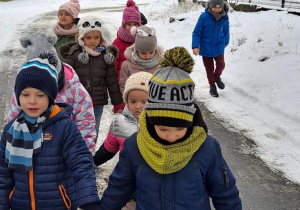 Dzieci idą w parach i sprawdzają ilość śniegu w okolicy furtki.