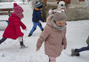 Troje dzieci wydeptuje ślady na śniegu.
