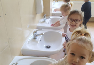 Dzieci w praktyce stosują poznaną technikę mycia rąk podczas mycia ich w łazience przedszkolnej.