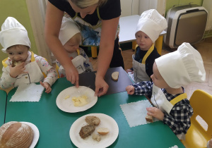 Przedszkolaki wybrany przez siebie rodzaj chleba smarują masłem, przy niewielkiej pomocy cioci.