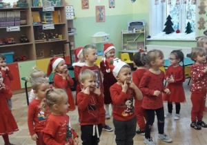 Przedszkolaki pokazują Mikołajowi podczas tańca swoje uśmiechnięte buzie.
