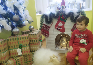Indywidualne zdjęcie chłopa siedzącego przy kominku., udekorowanym skarpetami na prezenty.