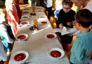 Dziewczynka bierze z talerzyka opłatek i dzieli się nim z innymi.