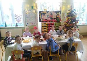 Grupa dzieci siedzi przy świątecznym stole.