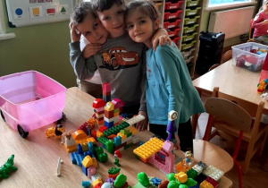 Troje dzieci buduje z klocków lego.