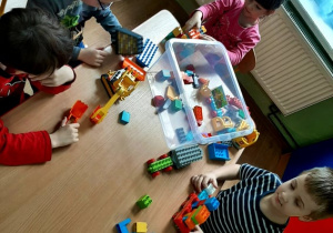 Czworo dzieci buduje z klocków lego.