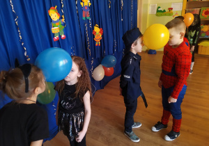 Dzieci trzymają balony między głowami w zabawie "Taniec z balonami"