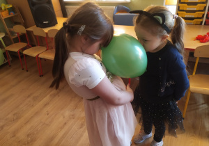 Dwie dziewczynki trzymają balon między głowami w zabawie "Taniec z balonami"