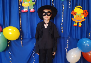 Chłopiec w przebraniu Zorro na tle dekoracji.