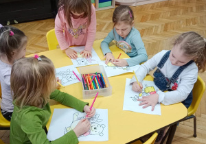 Dzieci przy stolikach kolorują obrazki Kubusia Puchatka.