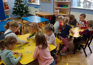 Dzieci przy stolikach układają puzzle.