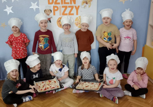 Dzieci prezentują przygotowane przez siebie pizzę.