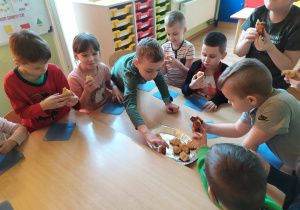 Dzieci przy stoliku jedzą upieczone rogaliki.