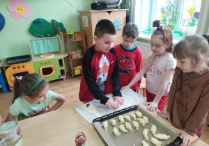 Chłopiec zwija ciasto, formując rogalika.