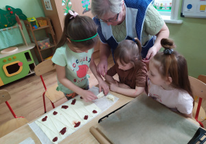 Dziewczynka zwija ciasto francuskie, tworząc rogalika.