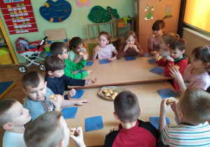 Dzieci przy stoliku smakują własnoręcznie przygotowane rogaliki.