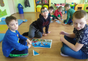 Trzech chłopców układa wiosenne puzzle.