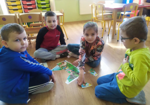 Dziewczynka i czterech chłopców układają wiosenne puzzle.
