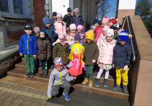 Dzieci z Marzanną przed budynkiem przedszkola.