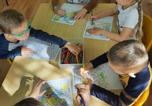 Dzieci przy stolikach kolorują Misia "Haribo" według kodu.