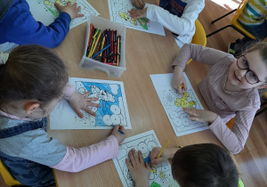 Dzieci przy stolikach kolorują Misia "Haribo" według kodu.