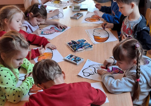 Przedszkolaki ozdabiają babeczki kolorowym lukrem i zjadają.