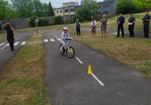 Dziewczynka pokonuje slalom na rowerze.