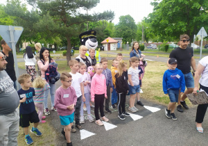 Grupa dzieci słuchająca pana policjanta objaśniającego poszczególne konkurencje w miasteczku ruchu.