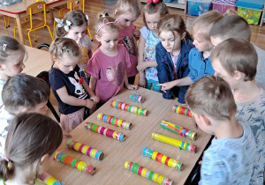 Dzieci zgromadzone wokół stolika przeliczają kolorowe instrumenty muzyczne.