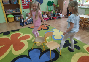 Dwie dziewczynki podczas zabawy z krzesłami.