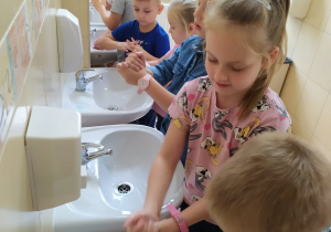 Grupa dzieci myje rączki w łazience.