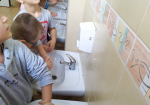 Grupa dzieci myje rączki w łazience.