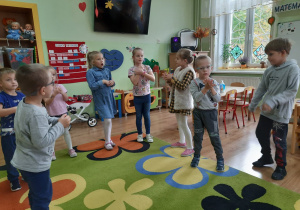 Grupa przedszkolaków naśladuje mycie rąk podczas zabawy ruchowej.