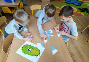 Trzech chłopców składa z części ilustrację wirusa.