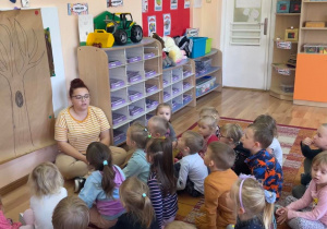 Dzieci wraz z nauczycielką siedzą na dywanie