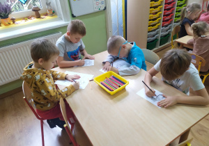 Przy stolikach 4 chłopców koloruje bajkowe ilustracje.