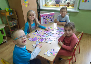 4 przedszkolaków układa puzzle "Myszka Miki".