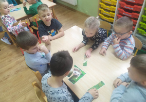 Grupa chłopców układa puzzle przedstawiające jeża.