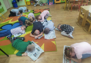 Starszaki leżą na dywanie na gazetach w zabawie "Jeżyki śpią".