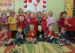 Dzieci wraz z Panią pozują do zdjęcia z lizakami w kształcie serca