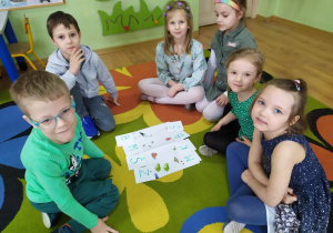 Dzieci siedzą w kole podczas wiosennej zabawy dydaktycznej.