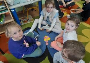 Dzieci w małych zespołach układają sylwety kwiatów z kolorowych kółek.