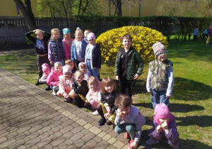 Grupa dzieci na tle kwitnącego krzewu forsycji.