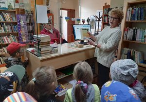 Pani bibliotekarka wyjaśnia dzieciom proces wypożyczania książek.